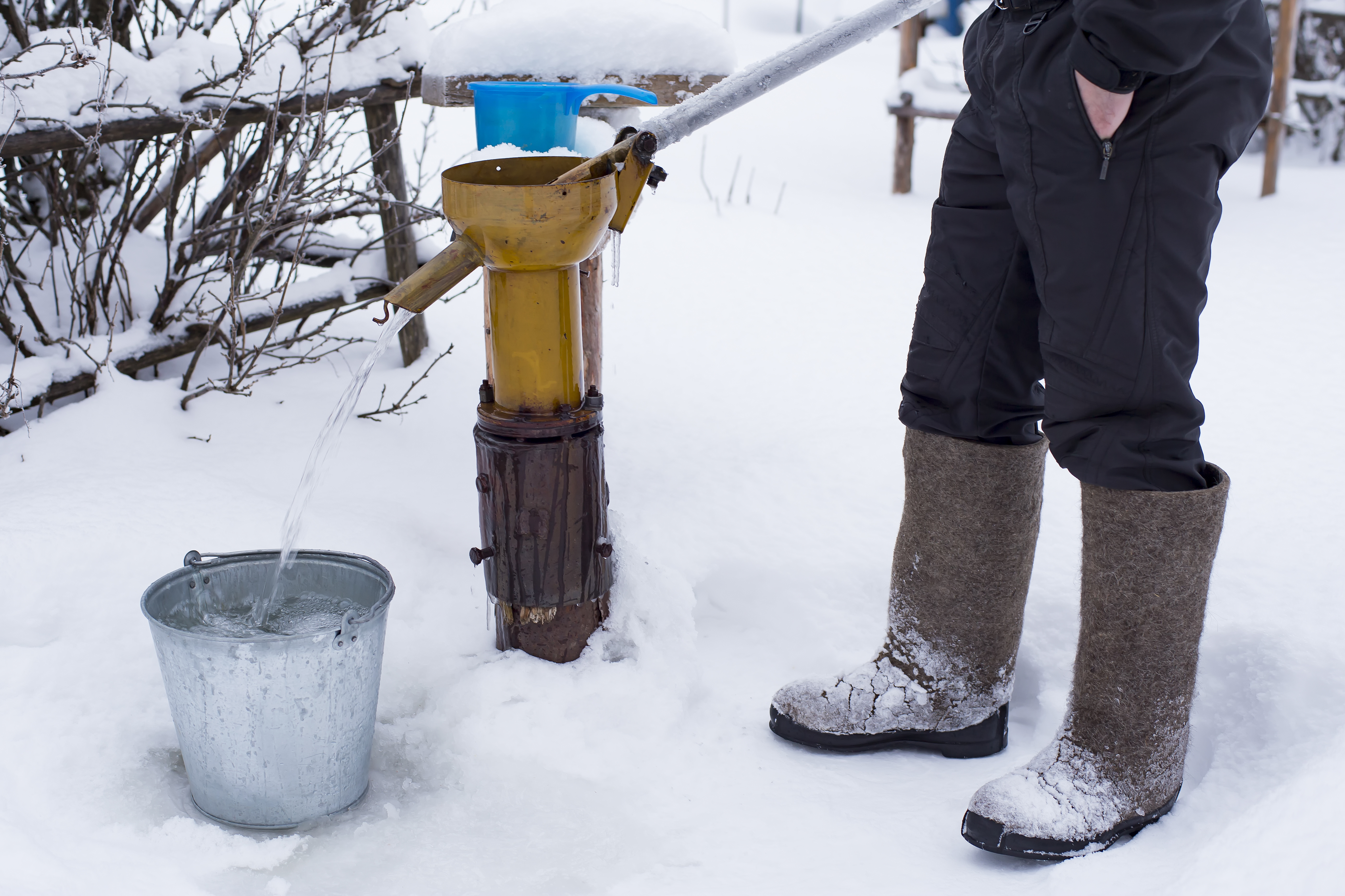 water pump being used to fill up a bucket in the snow