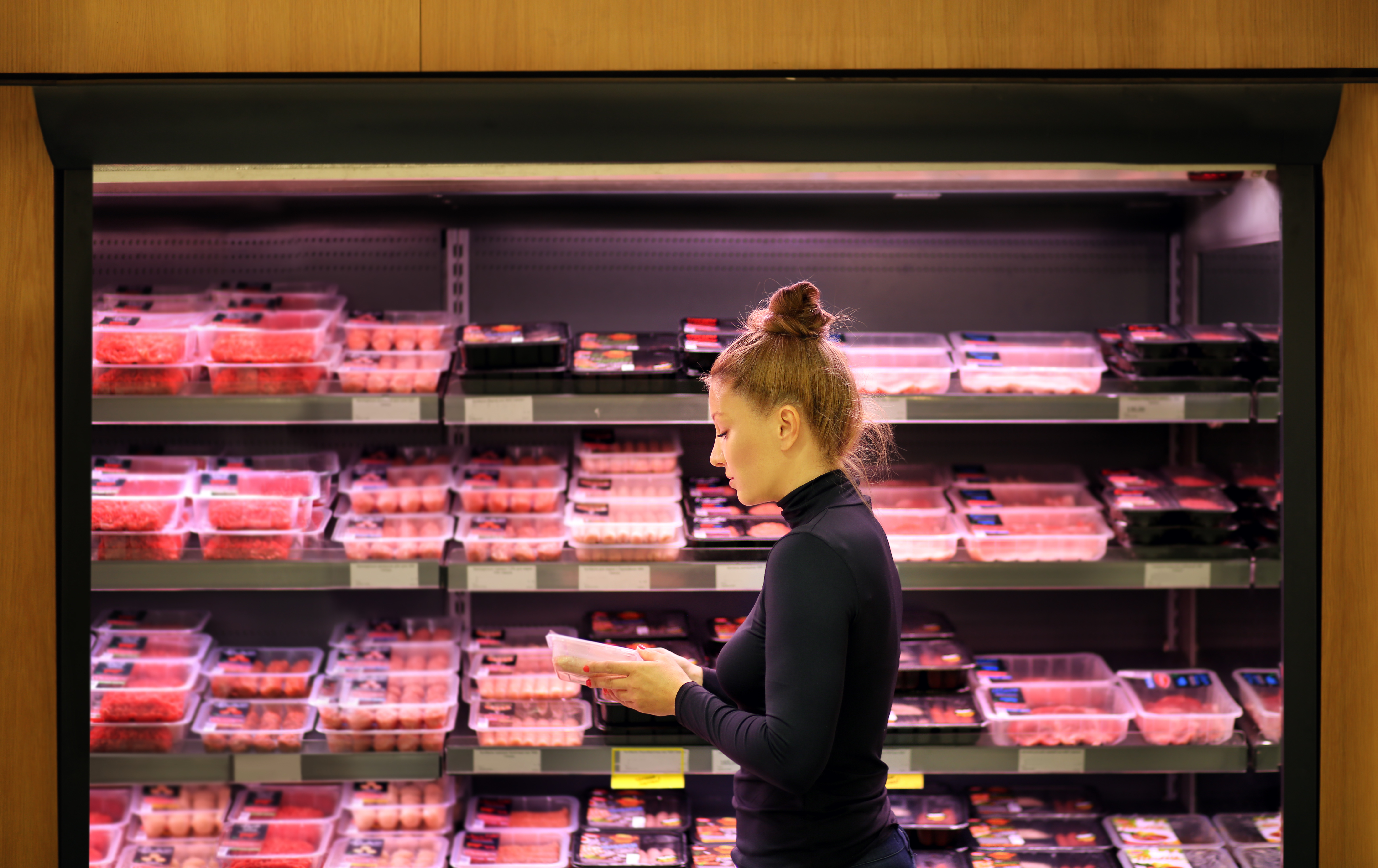 woman reads packaging of meat in a supermarket