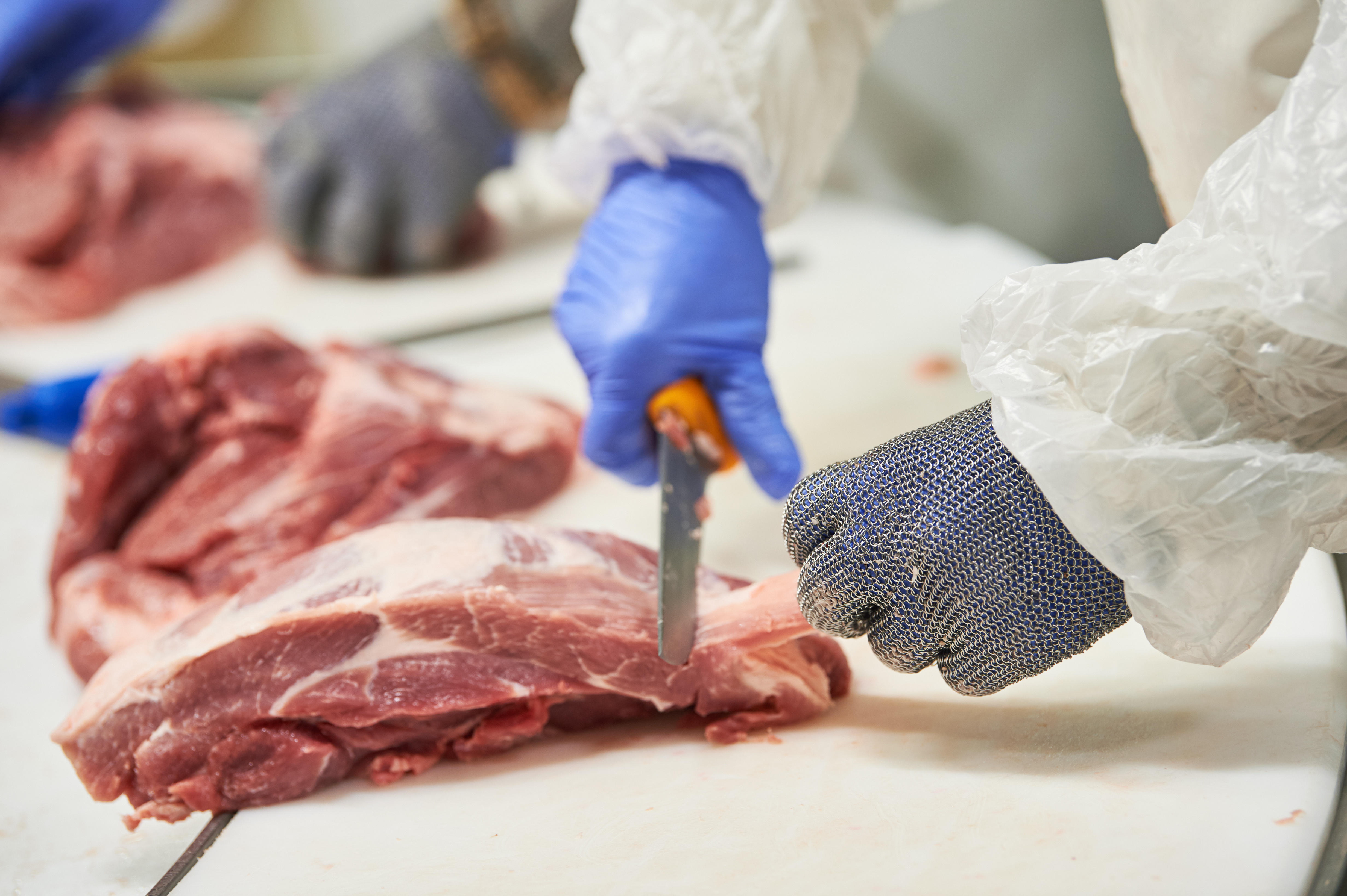 a butcher trims cuts of pork