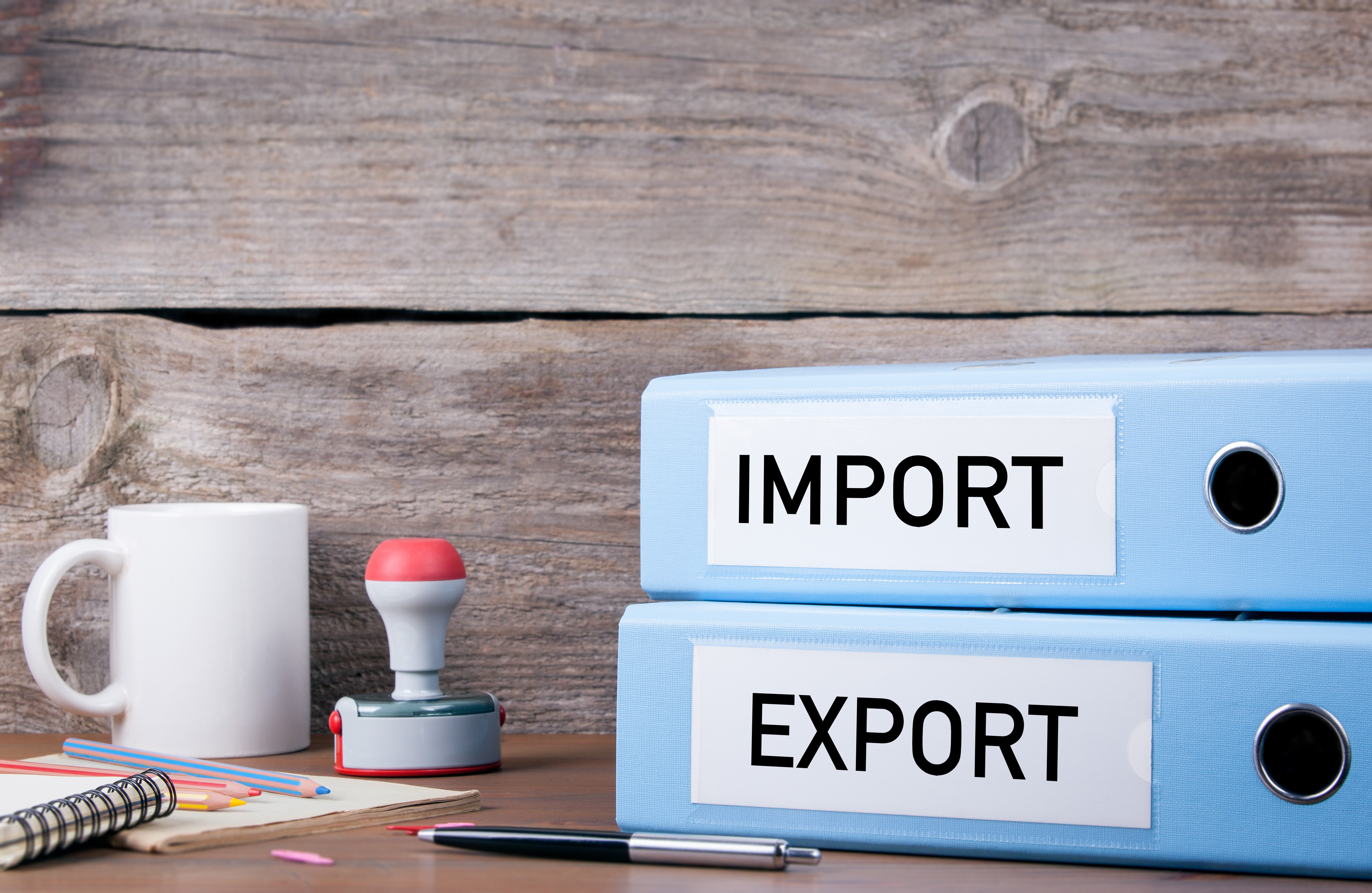 Two binders on a desk labelled "import" and "export"