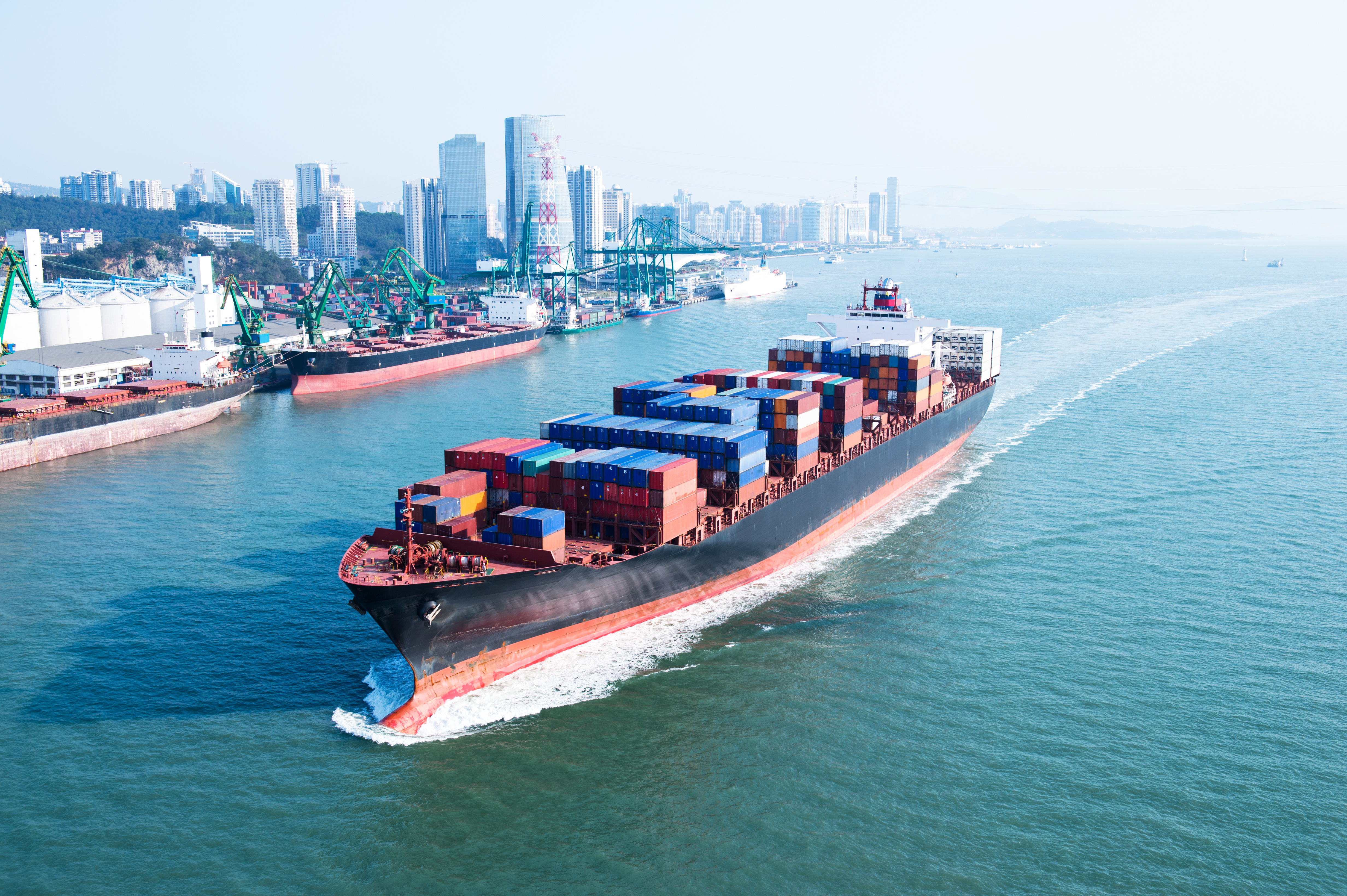 Container ship sailing next to a city skyline