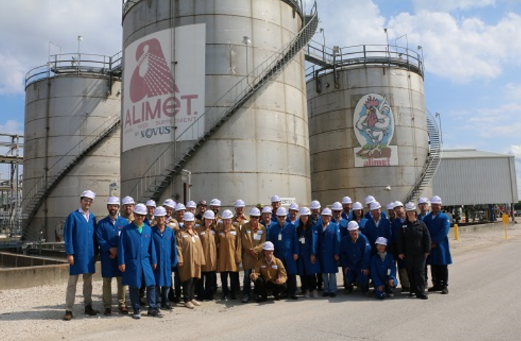 Group of workers in blue overalls pose in front of industrial coolers