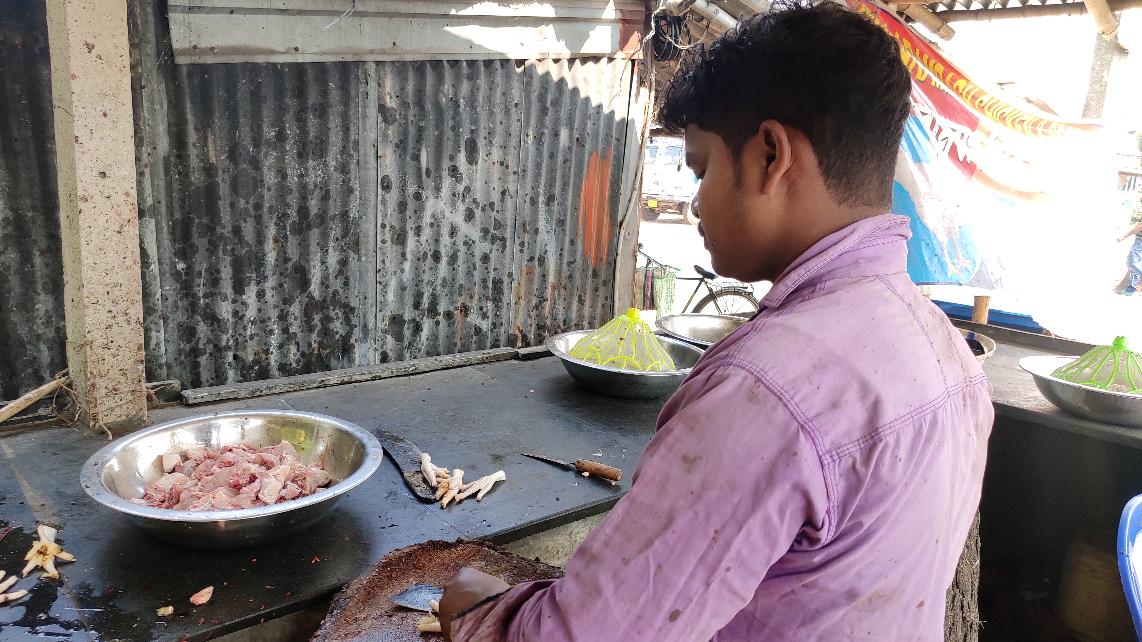 a man wearing a pink shirt looks at a bowl full of chicken meat