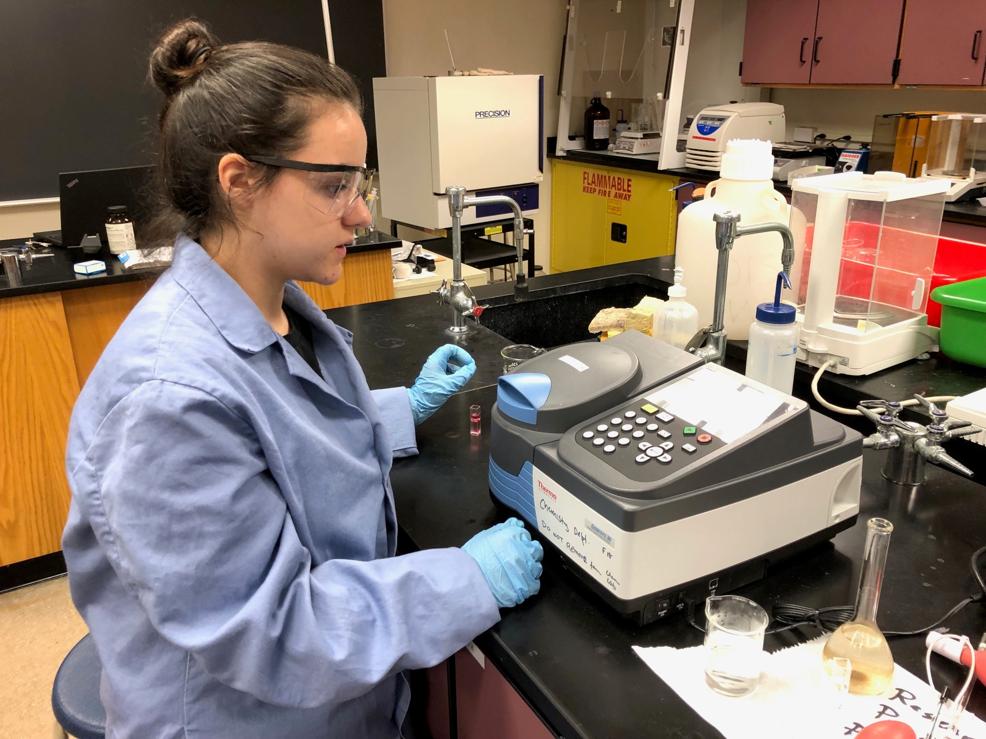 a woman wearing a lab cloak works at a device