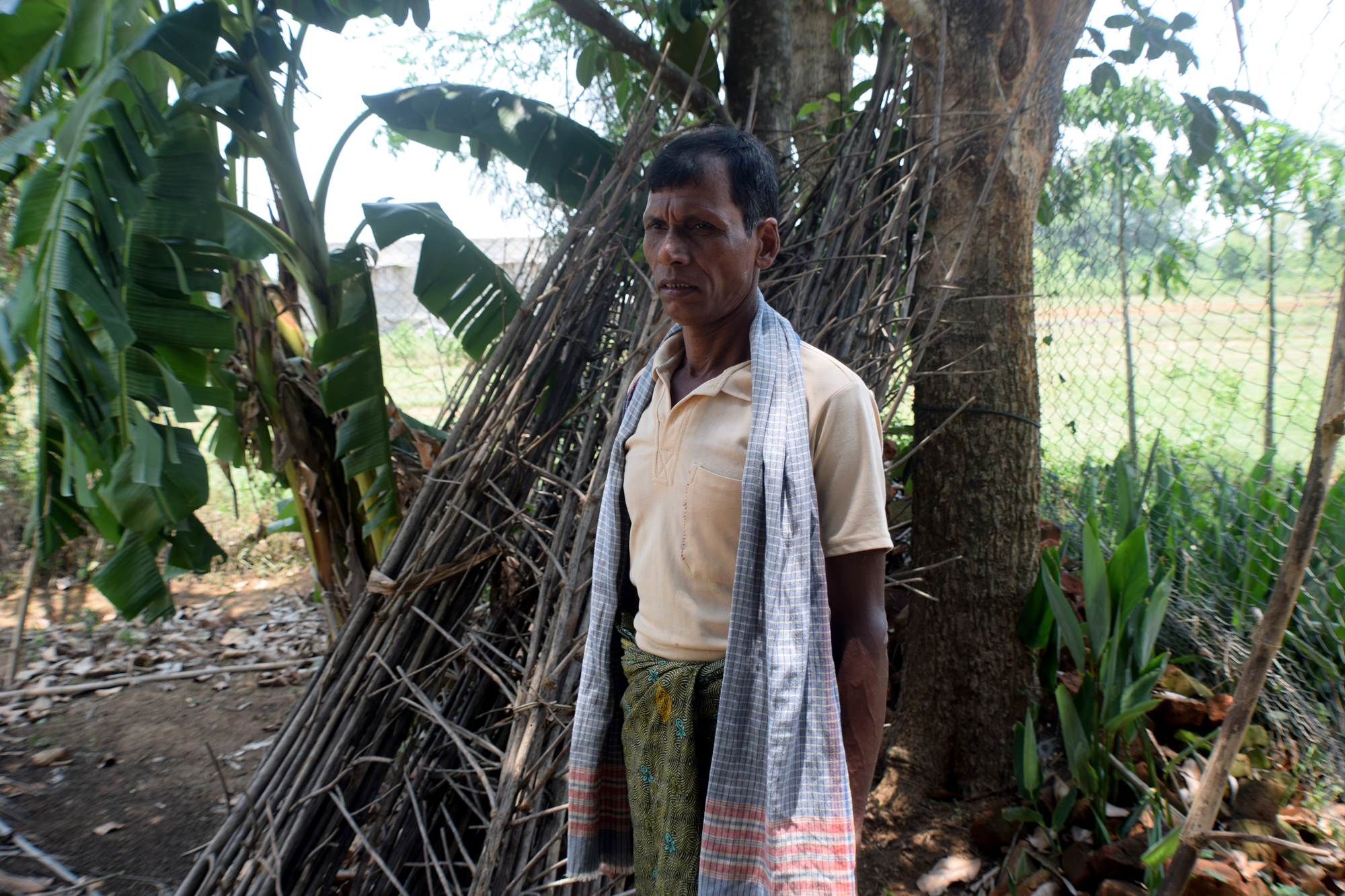 Indian man stands in a grassy area near his farm