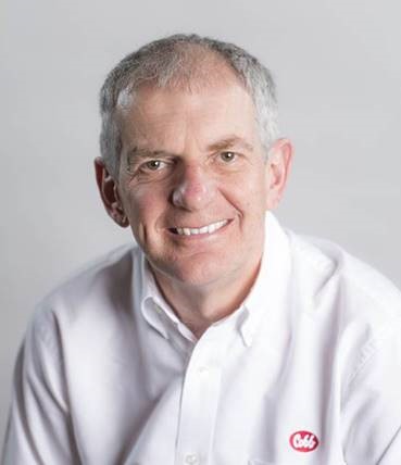 a haedshot of a man in a white shirt smiling; the red Cobb logo is on the shirt