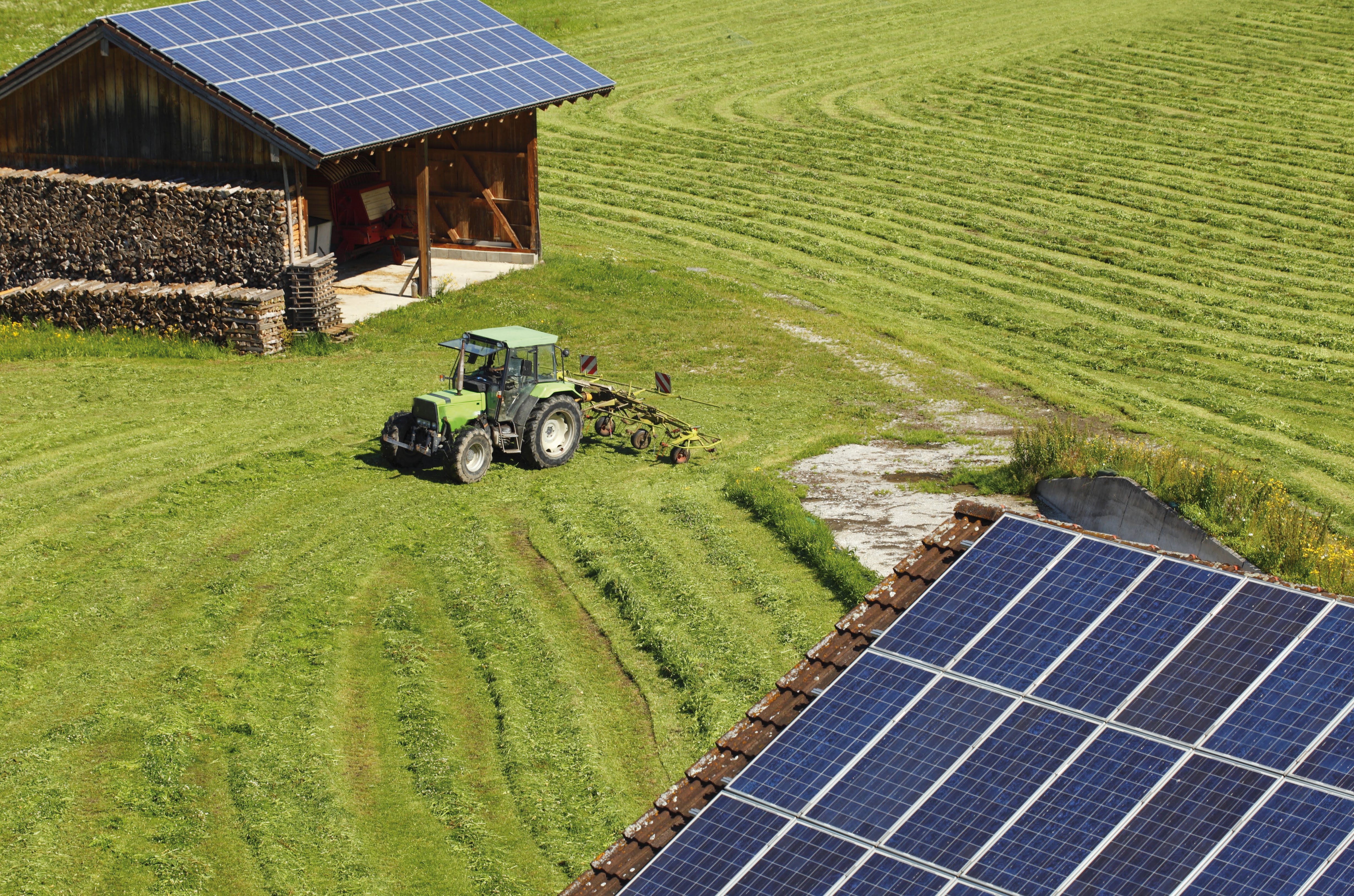 a farm in a field by a barn with solar panels on