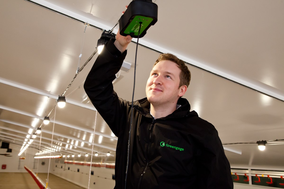 a man hangs a sensor in a barn